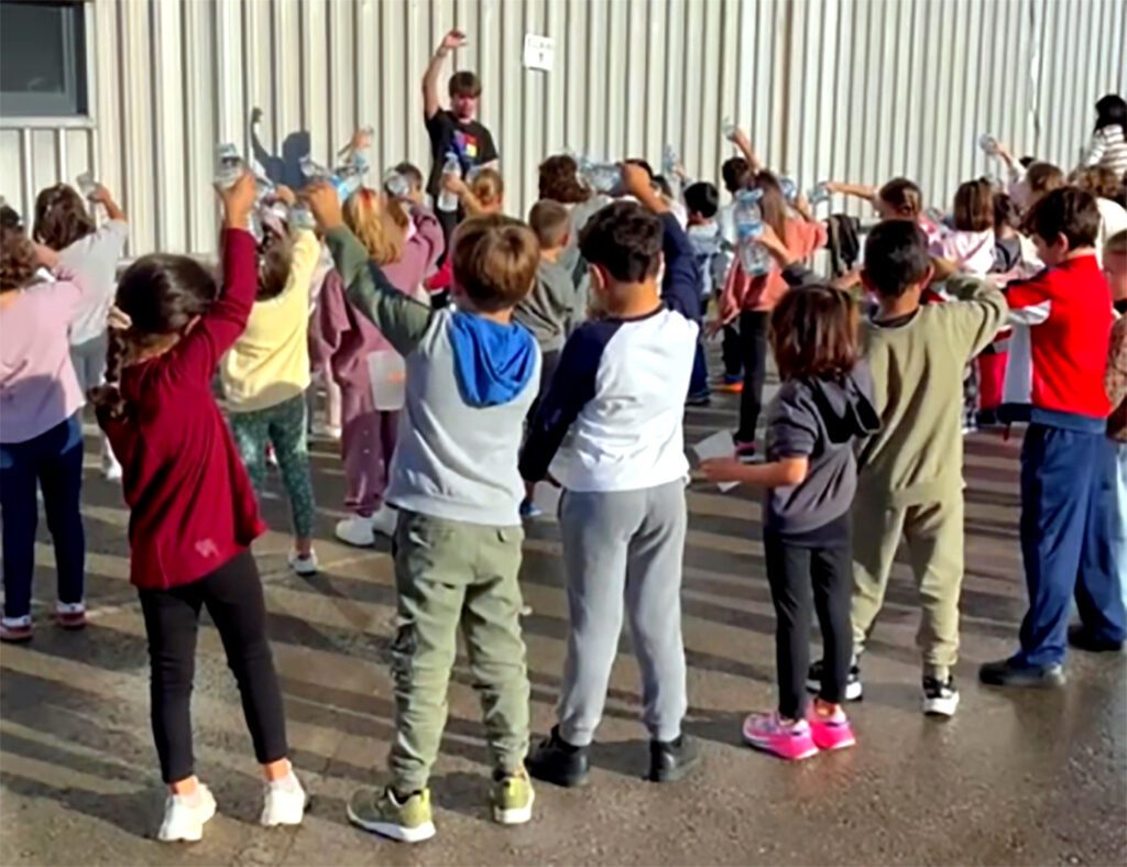 Escolinos participando nel taller d’echar con agua del Sidrocole del Día de la Mazana en Xixón