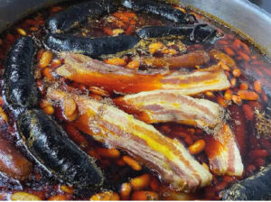 Fabada tradicional asturiana con compangu caseru (morciella, panceta y fabes mantegoses) servida nel chigre El Pintu, en La Pola Llaviana, Asturies. Platu icónicu de la gastronomía sidrera asturiana.