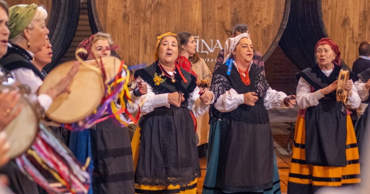Un grupu de pandereteres actúa delantre de los toneles de madera de Sidra Cortina