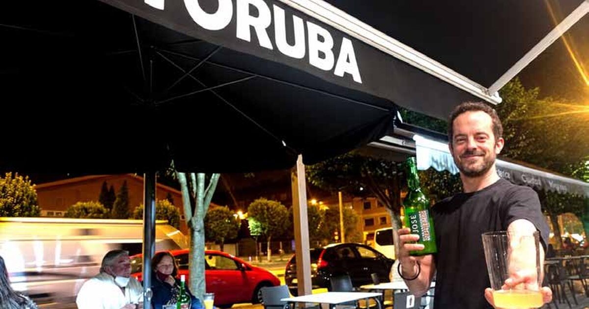 Camareru ofreciendo un culín de sidre nuna terraza