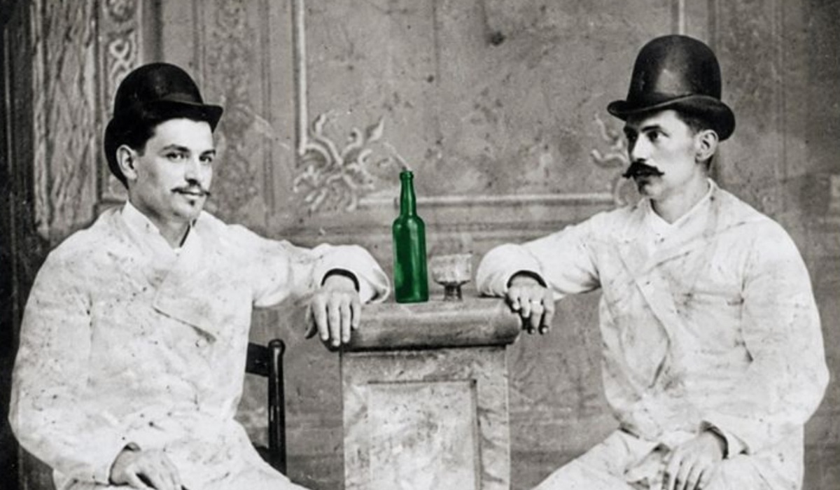 Dos emigrantes asturianos en Cuba, en 1885, con una botella de sidra y un vaso.