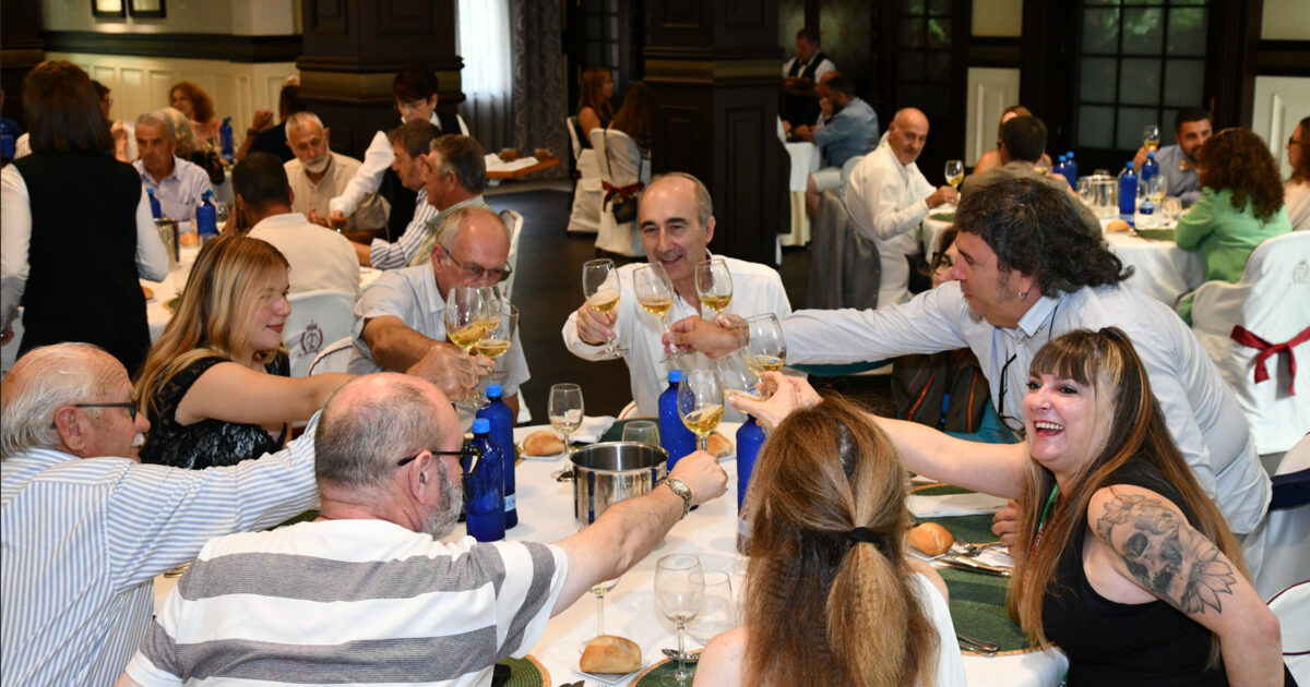 Un grupu de persones brinda con copes de sidre alredor d’una mesa.