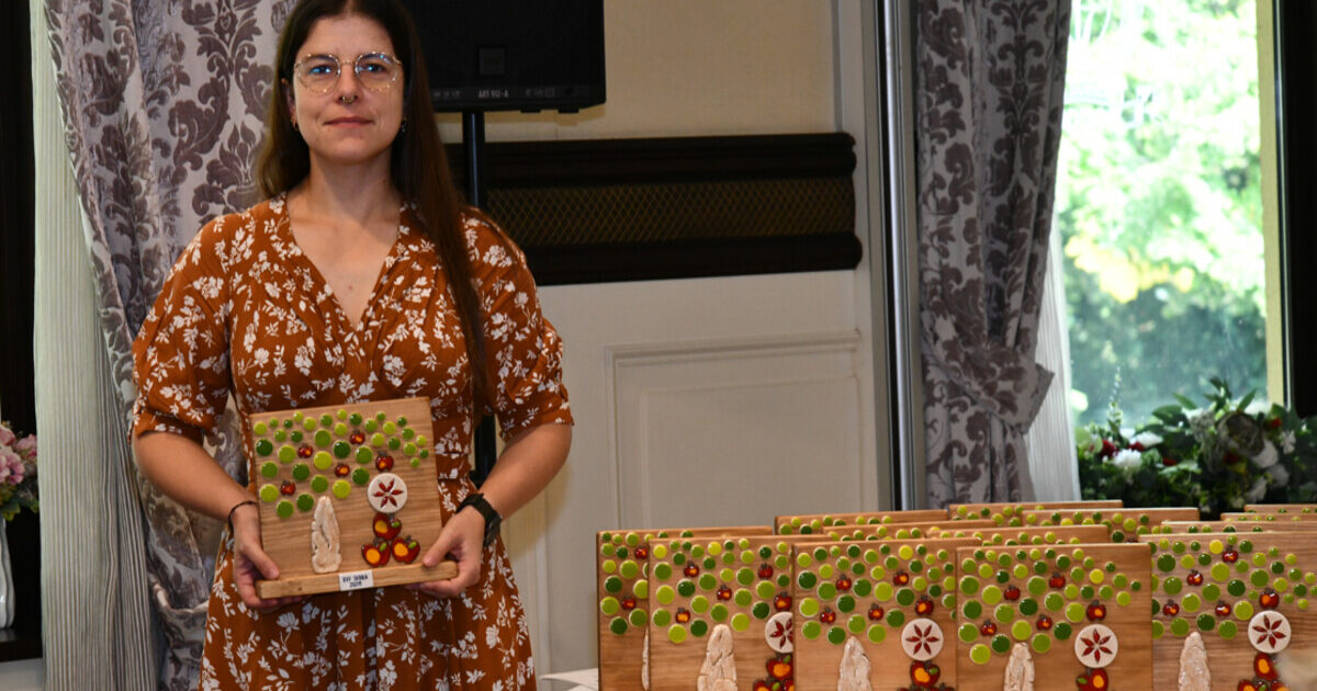 Woman holding a wooden trophy from the 16th SISGA in 2026.