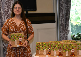 Woman holding a wooden trophy from the 16th SISGA in 2026.