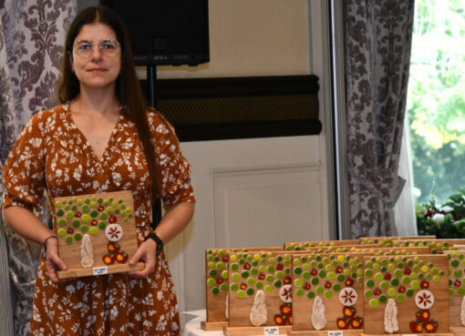 Woman holding a wooden trophy from the 16th SISGA in 2026.