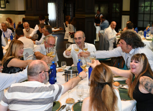 A group of people raise glasses of cider in a toast around a table.
